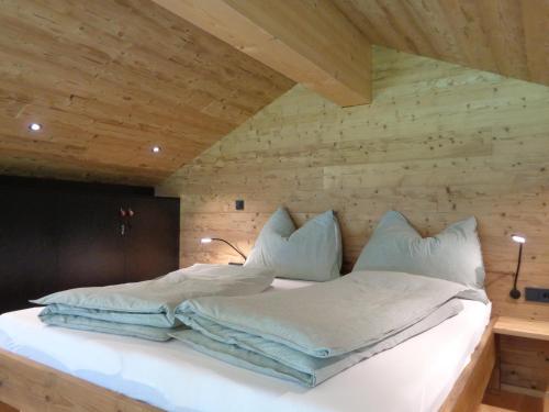een bed in een kamer met een houten muur bij Gargellen Lodge in Gargellen