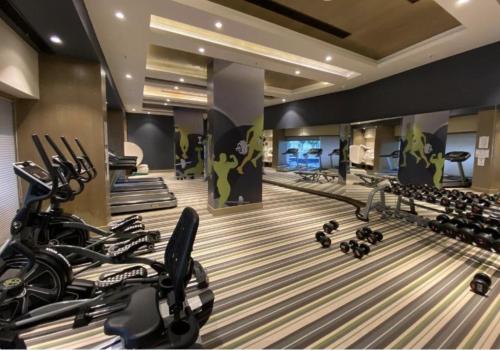 un gimnasio con filas de cintas de correr y bicicletas estáticas en Black Pearl DLF My Pad en Lucknow