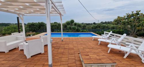 un patio con sillas blancas y una piscina en Regina di Puglia Casa Vacanze, en Monopoli