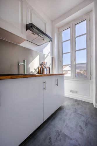 une cuisine avec des placards blancs et une grande fenêtre dans l'établissement MYAPPARTLAROCHELLE, à La Rochelle
