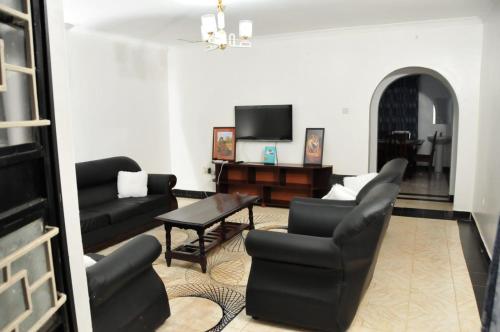 salon z czarnymi meblami i telewizorem w obiekcie Pacific Homes @milimani court, kakamega w mieście Kakamega
