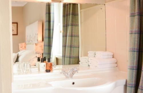 uma casa de banho com lavatório, espelho e toalhas em Scourie Hotel em Scourie