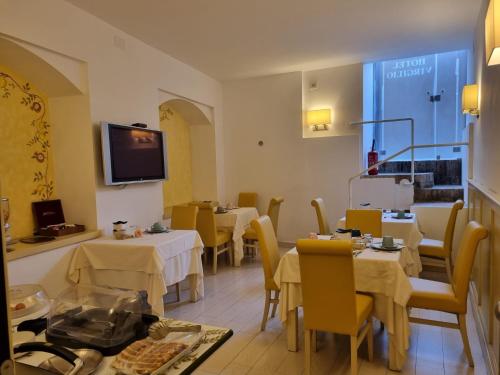un restaurante con mesas y sillas y TV en la pared en Hotel Virgilio, en Orvieto