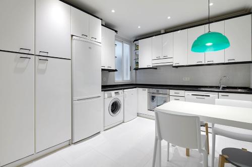 a kitchen with white cabinets and a white table and chairs at Mirakruz H by FeelFree Rentals in San Sebastián