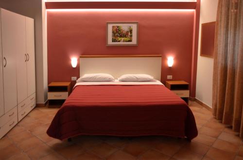 a bedroom with a bed with red walls and two tables at L'Infinito Agriturismo - Rooms & Breakfast in SantʼAlfio