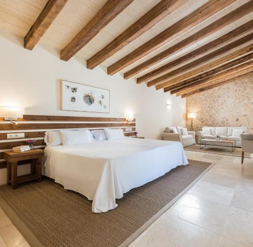 uma grande cama branca num quarto com tectos em madeira em Hotel Rural Son Mas - 4* em Porto Cristo