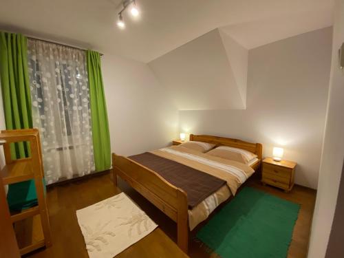 een slaapkamer met een bed en een raam met groene gordijnen bij Nad Grajcarkiem Pieniny in Szczawnica