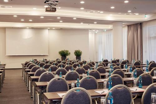 a conference room with tables and chairs and a whiteboard at HYPERION Hotel Hamburg in Hamburg