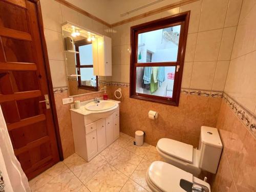 a bathroom with a toilet and a sink and a window at Casa Vacacional Nona in Caleta de Interián