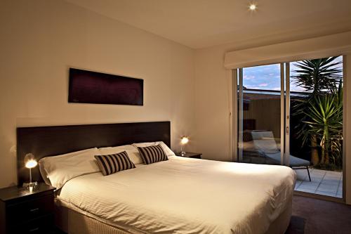 a bedroom with a large bed and a balcony at Brighton Bay Apartments in Melbourne