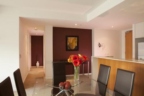 a dining room with a glass table with a vase of flowers at Brighton Bay Apartments in Melbourne