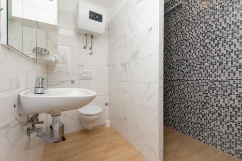 ein weißes Bad mit einem Waschbecken und einem WC in der Unterkunft House Coso in Podšpilje