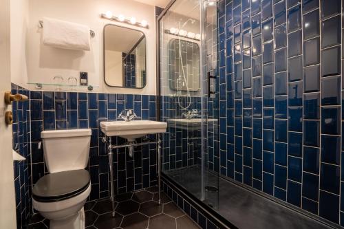 uma casa de banho em azulejos azuis com um WC e um lavatório em The Winchester Hotel and Spa em Winchester