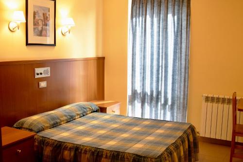 a bedroom with a bed and a large window at Pensio La Creu in Esterri d'Àneu