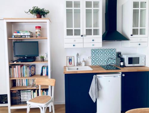 uma cozinha com armários azuis e brancos e um lavatório em Studio Tehani em Quiberon