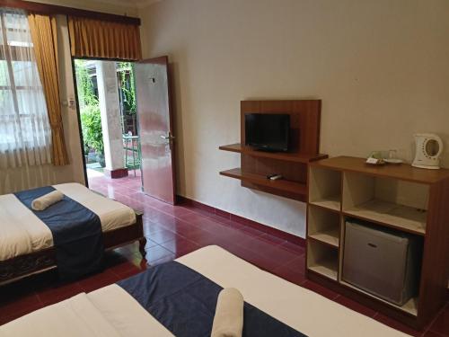 a hotel room with two beds and a television at Catur Adi Putra in Denpasar