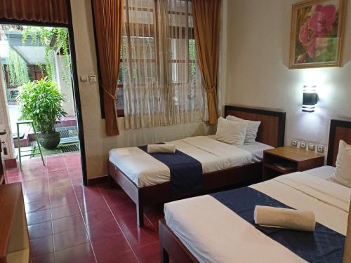 a hotel room with two beds and a window at Catur Adi Putra in Denpasar