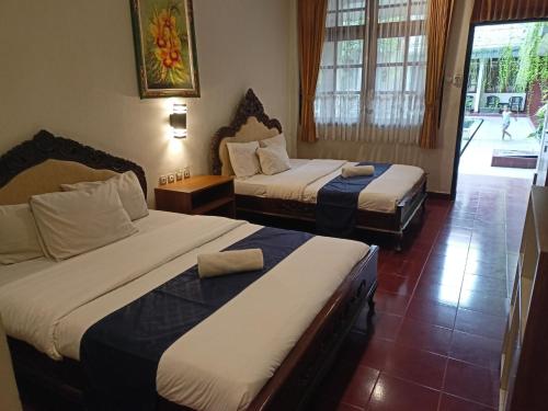 a hotel room with two beds and a window at Catur Adi Putra in Denpasar