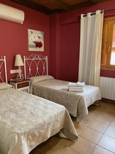 duas camas num quarto com paredes vermelhas em LA SOCIEDAD em Arens de Lledó