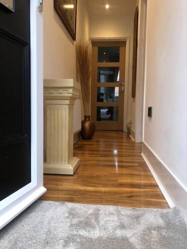 a hallway with wooden floors and a television and a door at Two Bedroom House Birchington ct79rn in Birchington