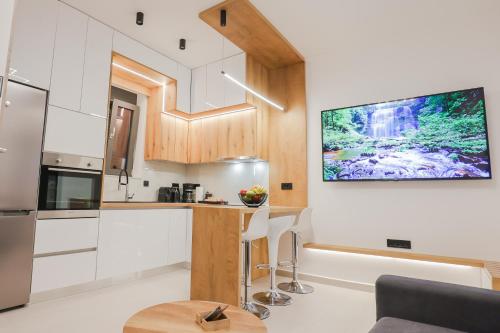 a kitchen with white cabinets and a tv on the wall at City Compass Luxury Suites in Rhodes Town