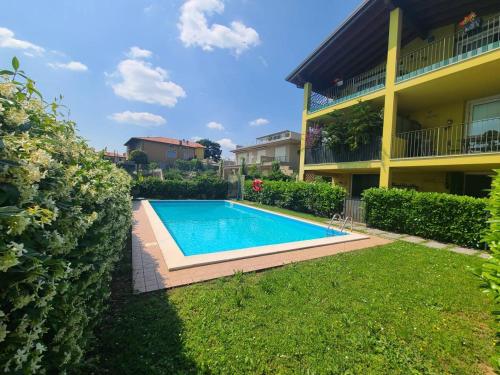 a swimming pool in a yard next to a building at Sandra Apartment in Lonato del Garda