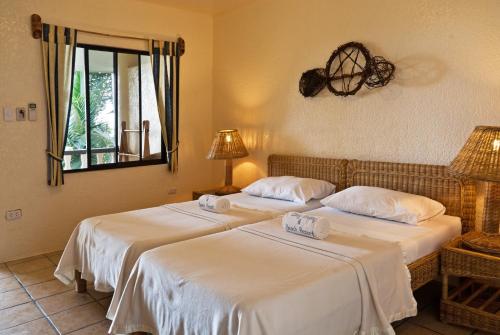 two beds in a room with a mirror at Easy Diving and Beach Resort in Sipalay