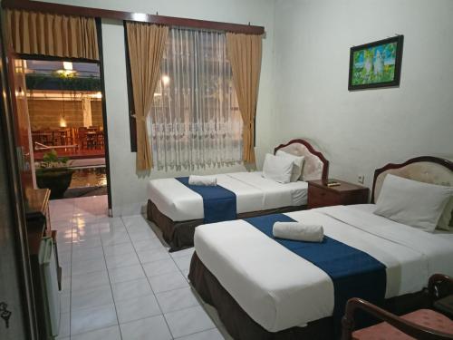 a hotel room with two beds and a balcony at Catur Adi Putra in Denpasar