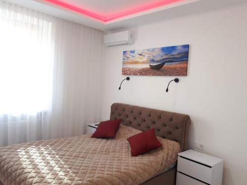 1 dormitorio con 1 cama con 2 almohadas rojas en Елітна квартира-студія ., en Ternopilʼ