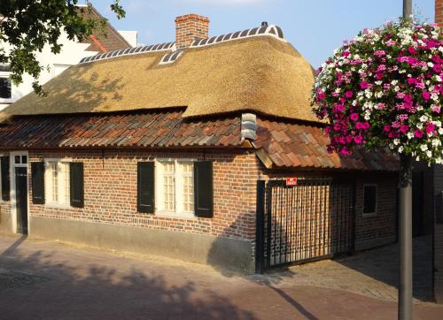 een bakstenen gebouw met een rieten dak en een bloeiende boom bij Het Kostershuisje in Nuenen