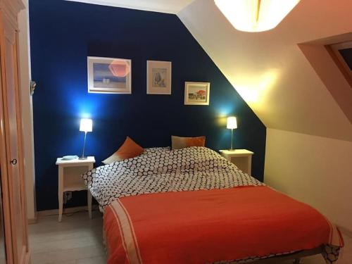 une chambre avec un lit avec un mur bleu dans l'établissement Maison de vacances à 8 min des plages par un chemin enchanteur, à Fouesnant