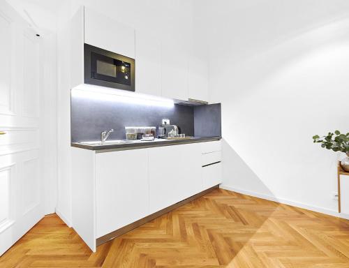 a white kitchen with a sink and a microwave at Residence Dlouha - Old Town in Prague