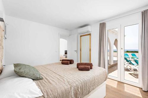 a white bedroom with a bed and a balcony at Villa Belvedere in Cala en Porter