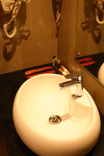 een witte wastafel in een badkamer met een spiegel bij Hotel Seven Lights in Ernakulam
