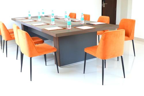 a conference table with orange chairs in a room at Hotel Seven Lights in Ernakulam