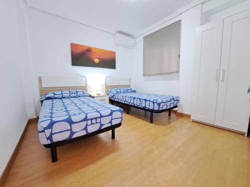 バレンシアにあるCéntrico apartamento en Valencia próximo parada de metro Ángel Guimeràの白い壁とウッドフロアの客室で、ベッド2台が備わります。