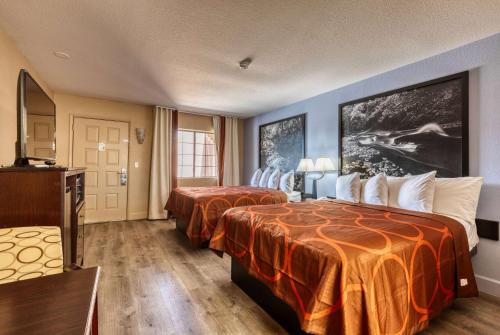 a hotel room with two beds with orange sheets at Super 8 by Wyndham Payson in Payson