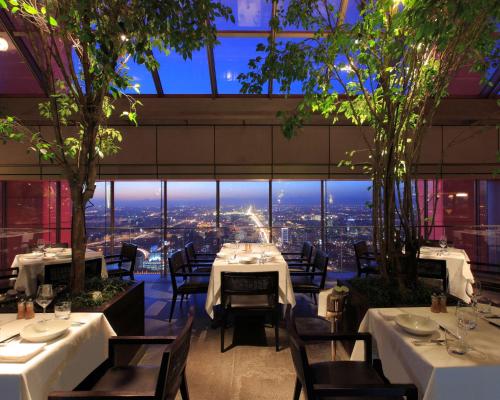 un ristorante con tavoli e sedie e vista sulla città di Park Hyatt Beijing a Pechino