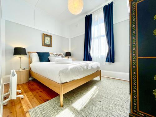a bedroom with a large bed with blue curtains at Barton Cottage in Katoomba