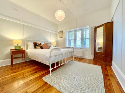 a bedroom with a white bed and a window at Barton Cottage in Katoomba