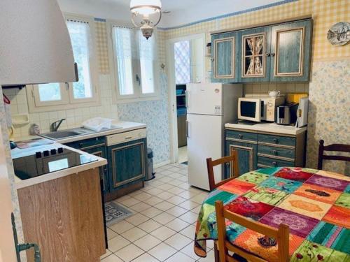 une cuisine avec une table et un réfrigérateur blanc dans l'établissement Appartement F3 avec Terrasse, Garage et Wifi - 4 Couchages - Proche Cures et Centre Ville - FR-1-703-113, à Amélie-les-Bains-Palalda