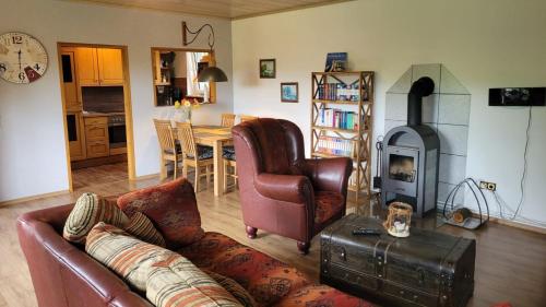 a living room with a leather couch and a fireplace at MoorBarg + MoorPütt in Sehestedt