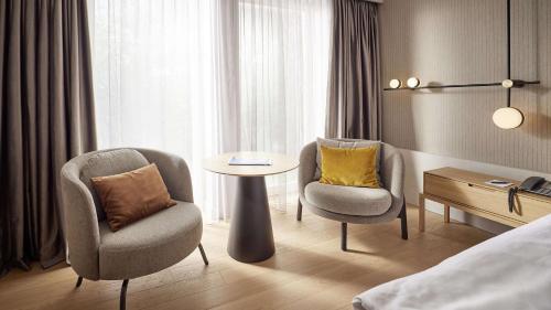 um quarto de hotel com duas cadeiras, uma mesa e uma cama em ATLANTIC Hotel Heidelberg em Heidelberg