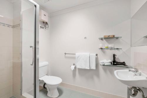 Baño blanco con aseo y lavamanos en Metro Hotel Perth City en Perth