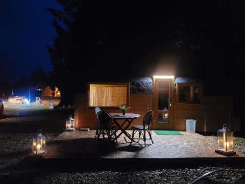 ein Tisch und Stühle vor einem Haus in der Nacht in der Unterkunft Brīvdienu namiņi Kalnozoli in Indrāni