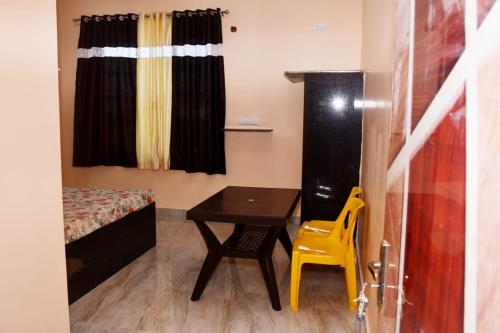 Habitación pequeña con mesa, cama y silla en Shriya Inn, en Malvan