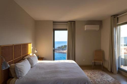 a bedroom with a bed with a view of the ocean at Sounio Villa Poseidon Temple View in Sounio