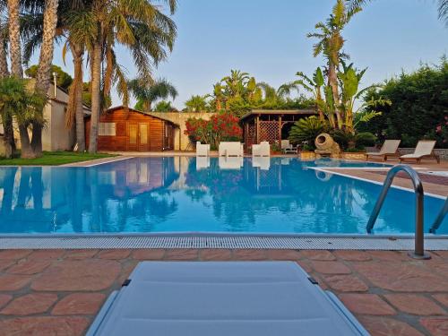 - une piscine d'eau bleue avec des palmiers dans l'établissement Villa Sara, à Borgo Bonsignore
