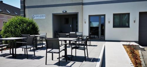 a patio with tables and chairs in front of a building at Das Joes Frühstückspension 