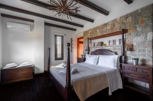 a bedroom with a large bed and a stone wall at Villa Vicanti in Mesokhórion